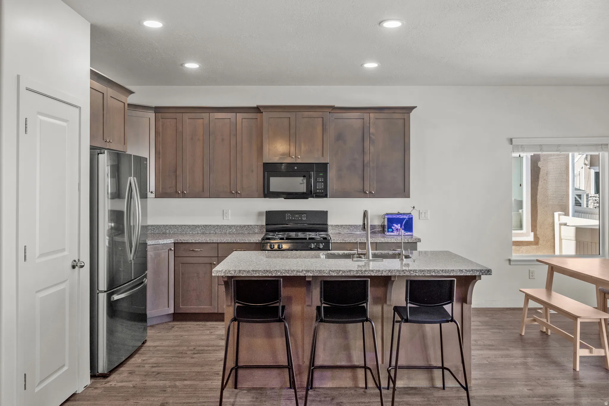 Kitchen featuring wood-finish flooring, recessed lighting, and a center island with sink