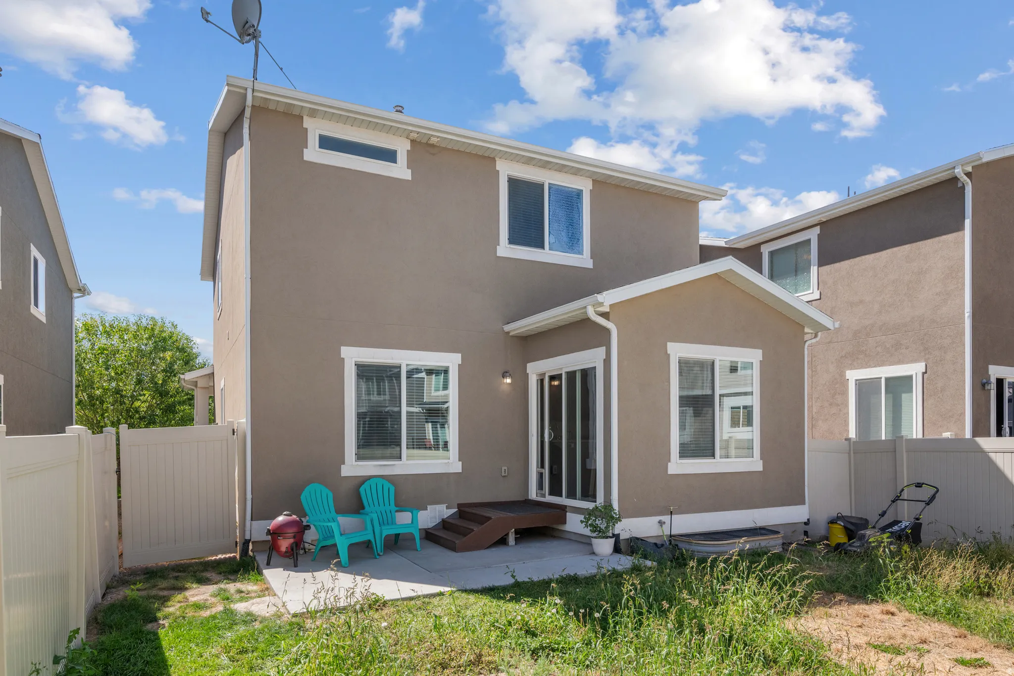 Stucco exterior featuring multiple windows, a sliding glass door, and a private patio with a deck