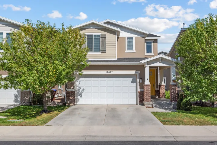 Two-story stucco and siding exterior with an attached garage, covered entryway, brick-clad columns, and a concrete driveway