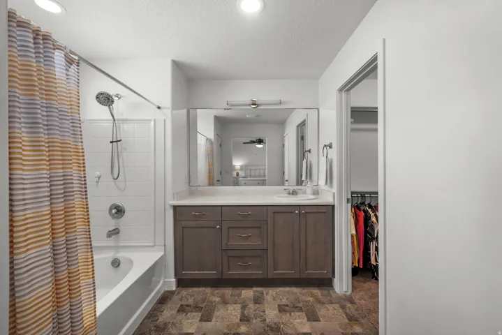Bathroom featuring a vanity with dark wood-finish cabinetry, a large mirror, a shower-over-tub combination with white subway tile surround, and recessed lighting