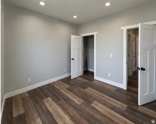 Recessed lighting, wood-finish flooring, white trim, and white doors with black hardware