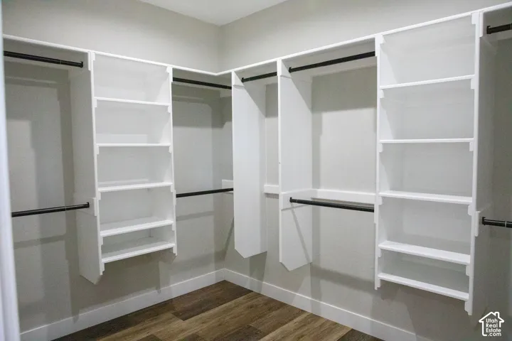 Built-in closet organization system featuring white shelving, black hanging rods, and wood-finish flooring