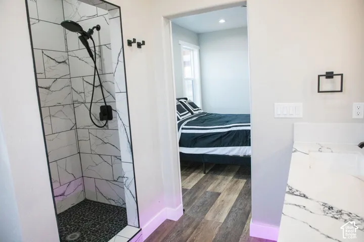Shower with white and black tiled walls, black pebble flooring, and matte black fixtures