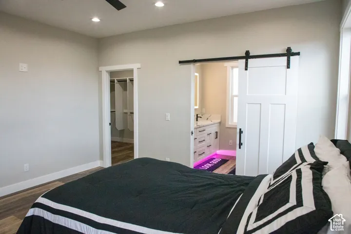 Wood-finish flooring with recessed lighting, a ceiling fan, and a white barn door