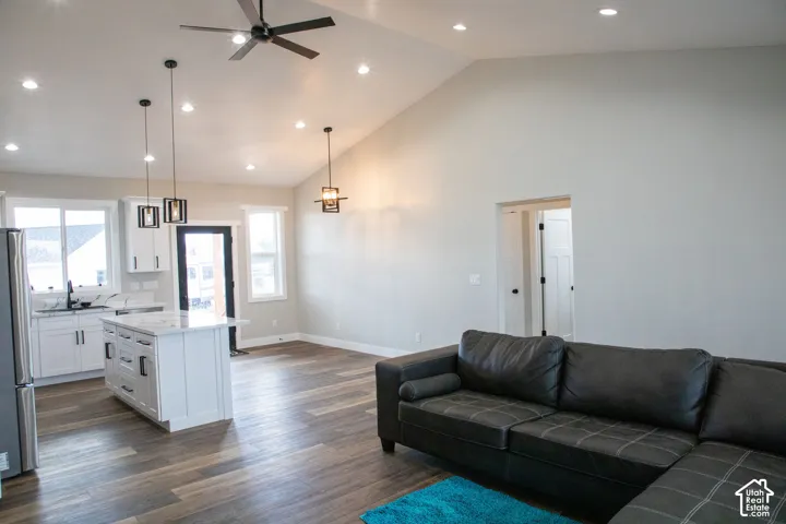 Vaulted ceilings with recessed lighting, wood-finish flooring, and white kitchen cabinetry