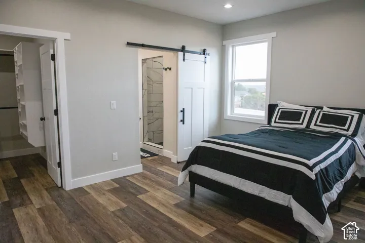 Wood-finish flooring, white trim, recessed lighting, and a white barn door