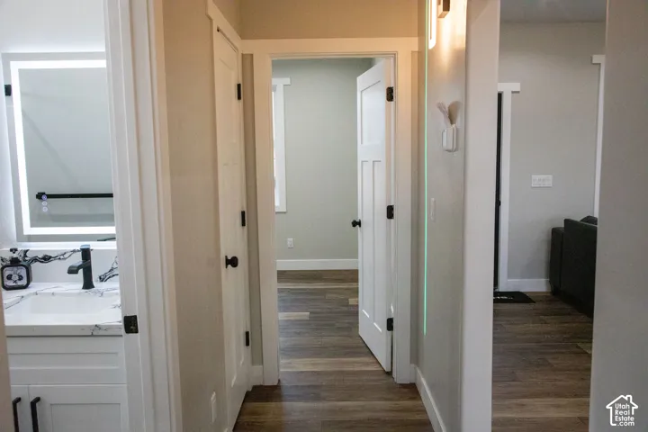 Wood-finish flooring throughout, white paneled doors with black hardware, and an illuminated vanity mirror with a black faucet