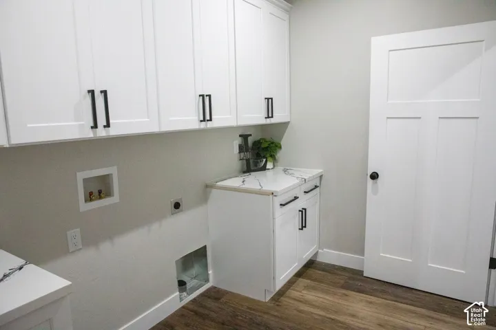 White shaker cabinetry with matte black hardware, wood-finish flooring, and a white panel door