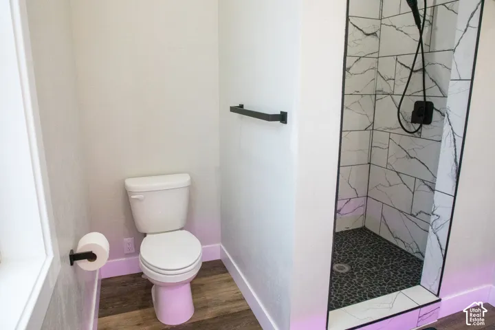Walk-in shower with large-format marble-look wall tiling and a pebble floor, featuring a matte black shower system