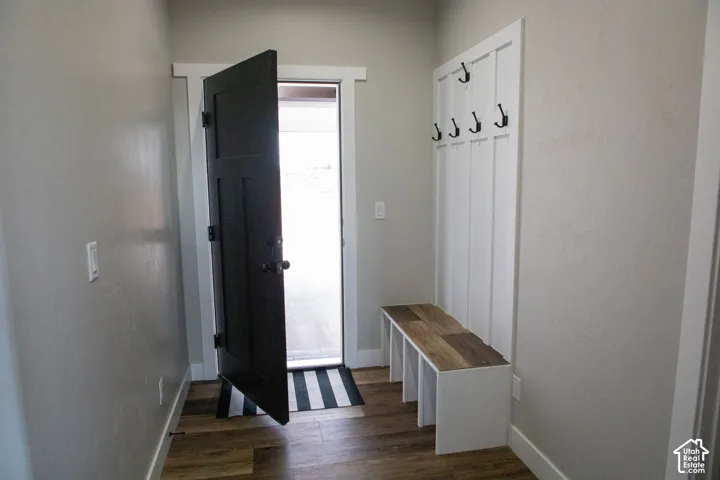 Wood-finish flooring with a white trim, a built-in bench with a wood-finish top, and a white coat rack with black hooks