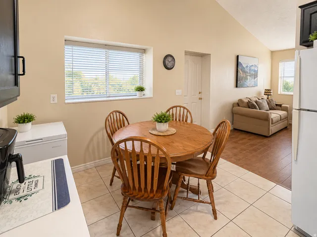 Vaulted ceiling, tile flooring, wood-finish flooring, white appliances, and a built-in window