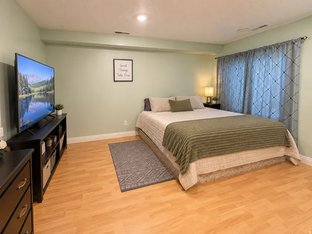 Recessed ceiling lighting, wood-finish flooring, light-toned wall paint, and window with full-length draperies