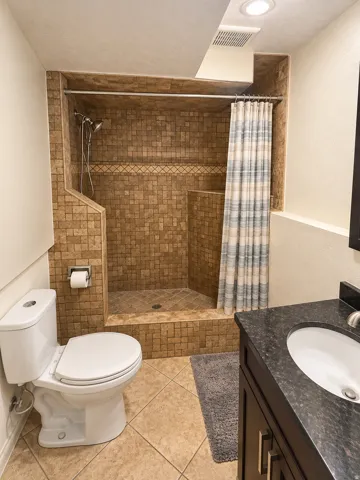 Tiled shower with decorative accent border, a built-in shower niche, and dual shower heads