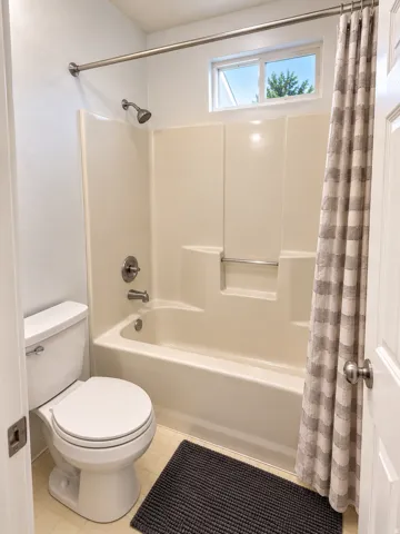 Bathtub and shower combination with a single-handle faucet, chrome finishes, and a high window