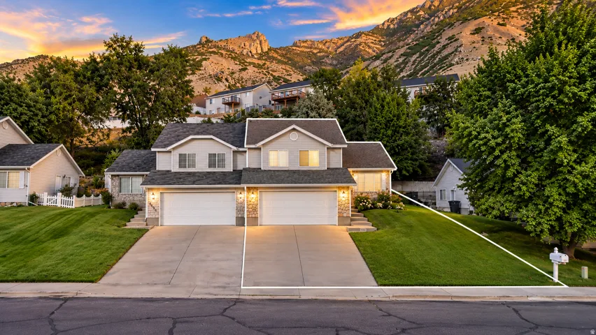Two-story residence featuring a dual two-car garage, stone façade accents, and a sloped front lawn
