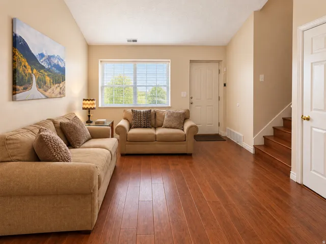 Wood-finish flooring, vaulted ceiling, and natural light from a large window