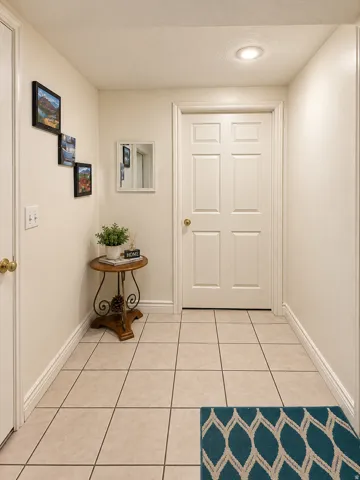 Recessed ceiling lighting illuminates a tiled flooring entry, featuring a paneled door with a brass-toned doorknob