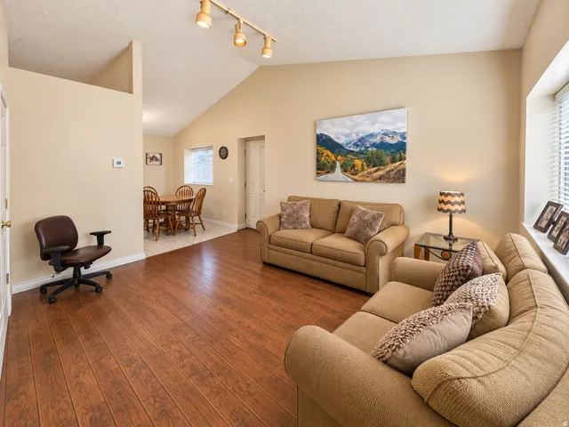 Vaulted ceiling with track lighting, wood-finish flooring, and white window blinds