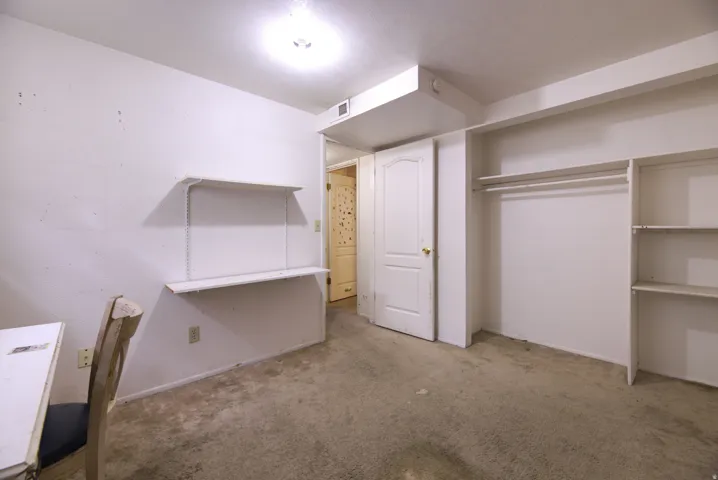 Recessed ceiling light, built-in shelving, integrated desk, and carpeted flooring