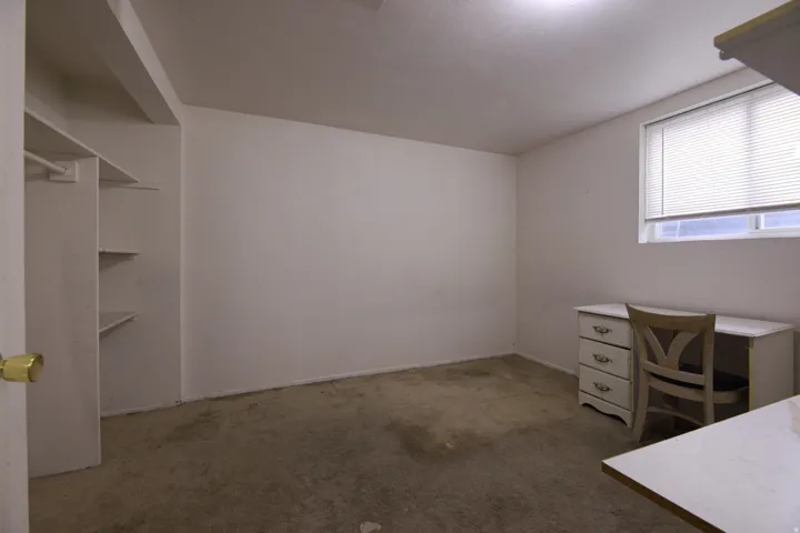 Built-in shelving, flush-mounted ceiling light, and a single window with horizontal blinds