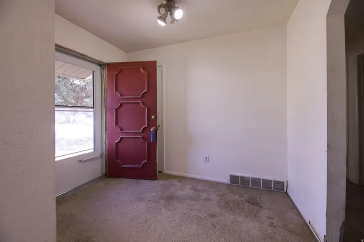 Entryway featuring a decorative red panel door, a large fixed-pane window, and a flush-mount ceiling light fixture