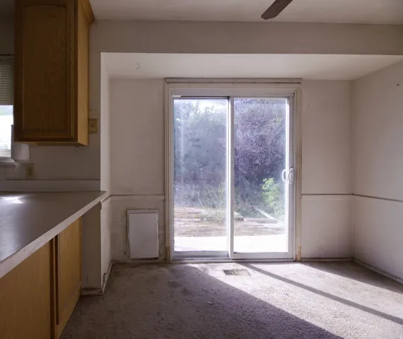 Sliding glass door opening to outdoor area, wood-finish cabinetry, and ceiling fan