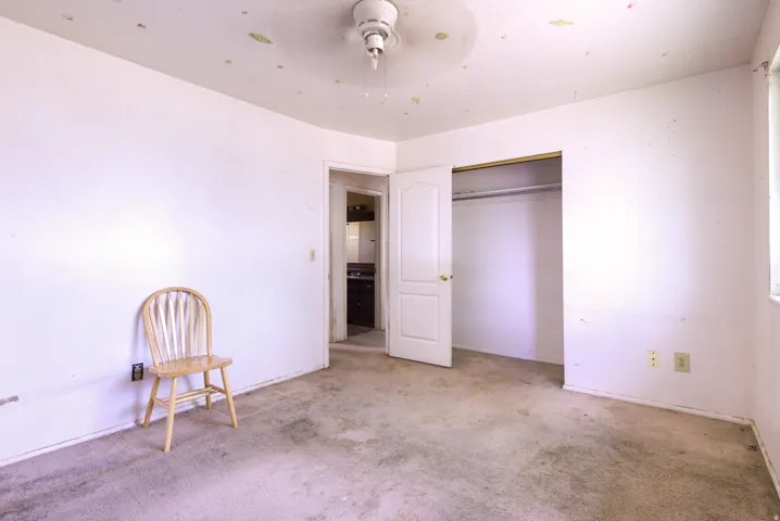 Interior room with carpeted flooring, a ceiling fan, and a built-in closet with sliding doors