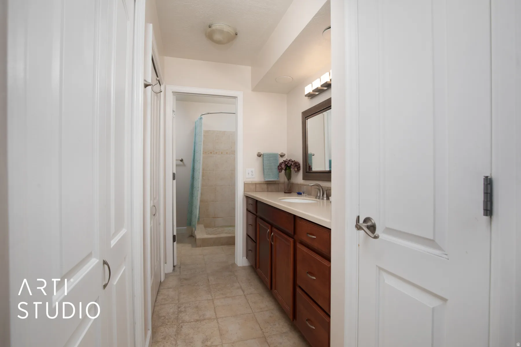 White paneled doors, wood-finish vanity with countertop, undermount sink, and tiled flooring