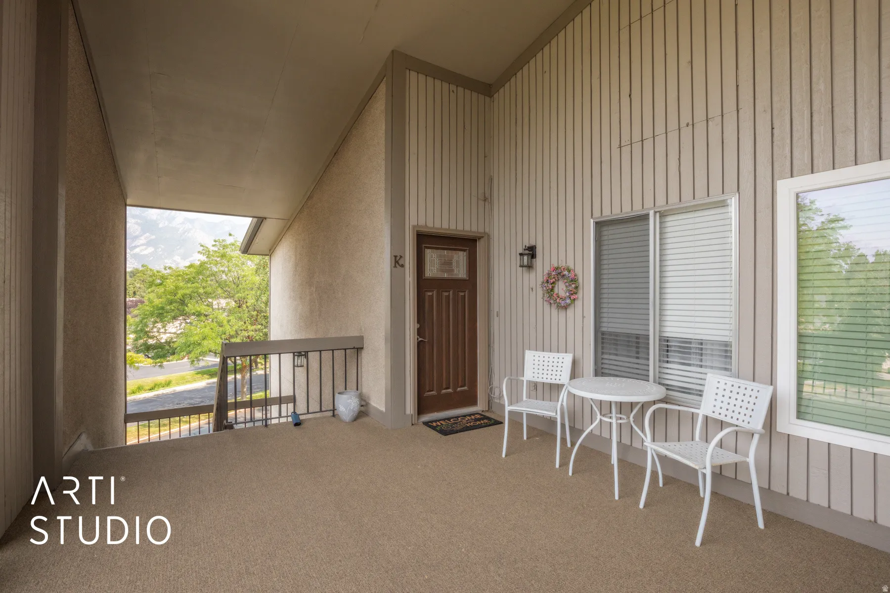 Covered entry with durable textured flooring, a solid wood entry door with clear glass panels, and exterior wall-mounted lighting