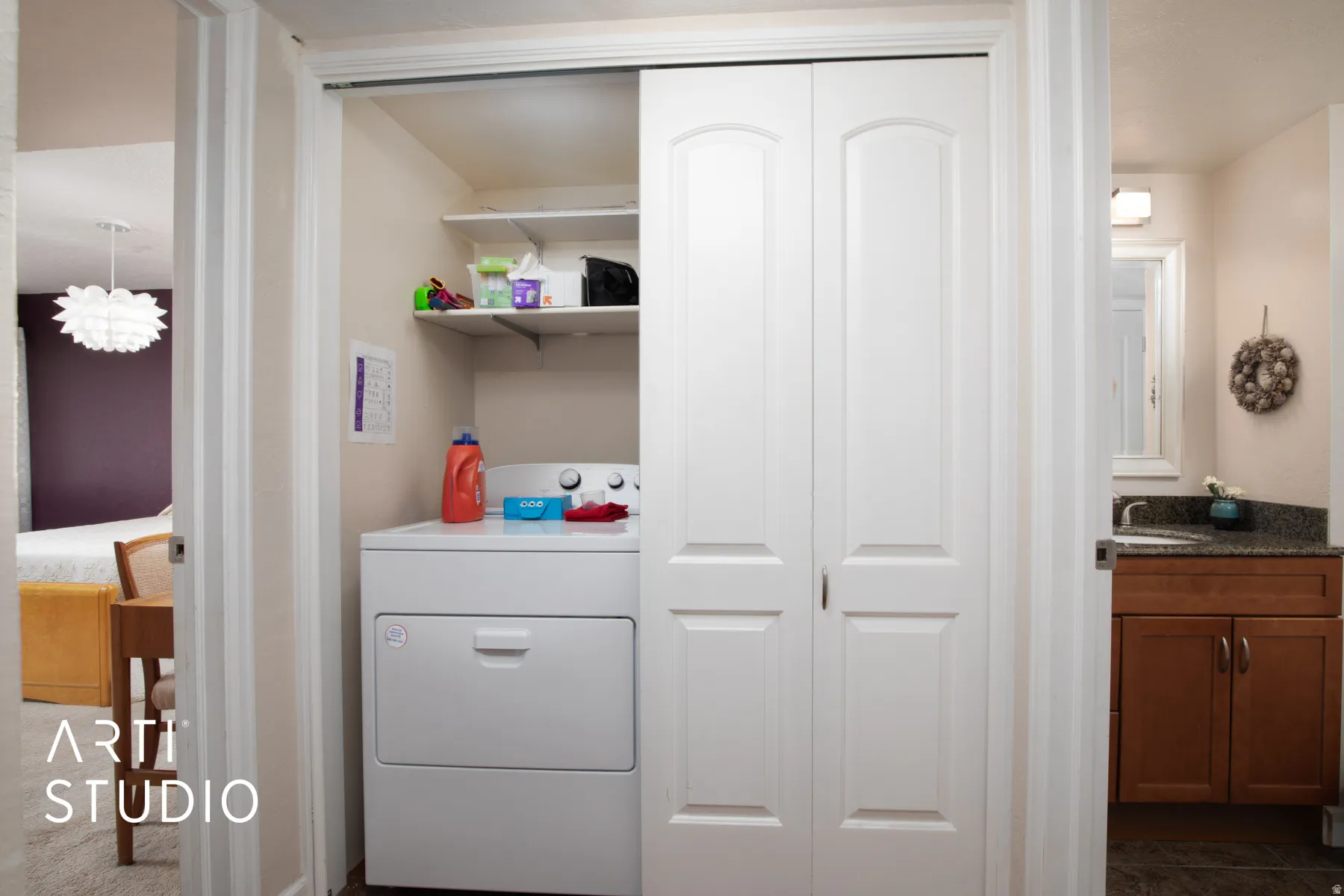 Laundry area with bi-fold doors, integrated shelving, and a dryer appliance