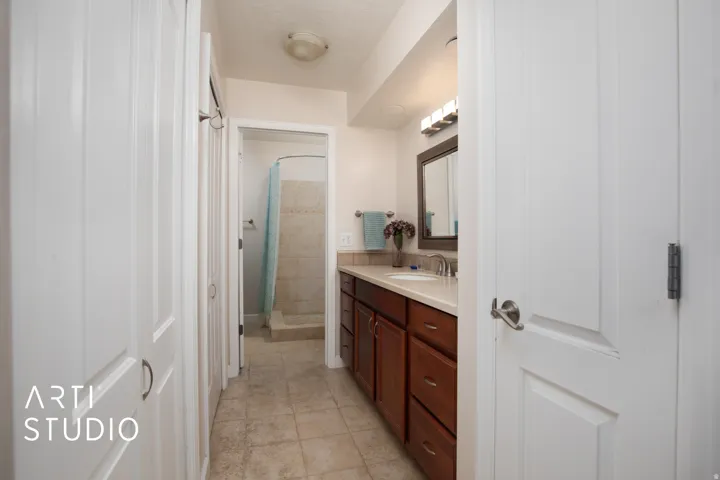 White paneled doors, wood-finish vanity with countertop, undermount sink, and tiled flooring
