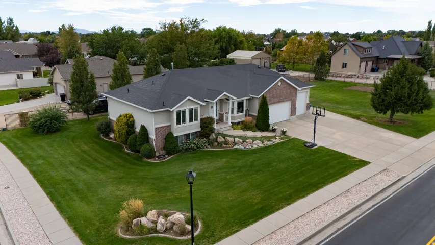 Brick and siding exterior with a dark shingle roof, two-car garage, established front landscaping, and concrete driveway