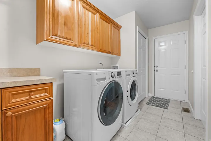 Neutral wall paint, wood-finish cabinetry, light-toned countertop, tile flooring, and a white paneled door