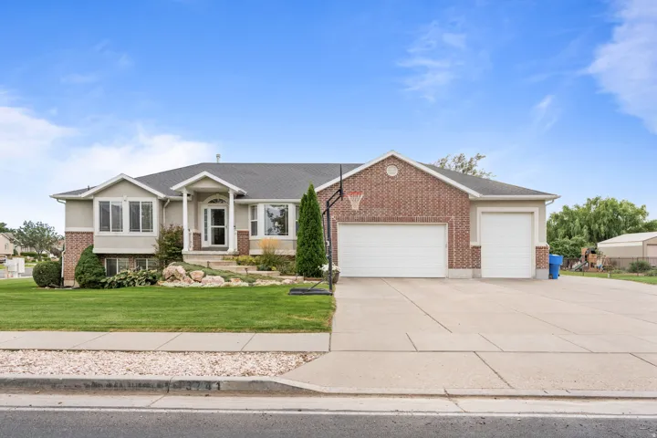Brick and stucco exterior with multiple bay windows, a covered entry, and a multi-car driveway leading to two garage doors