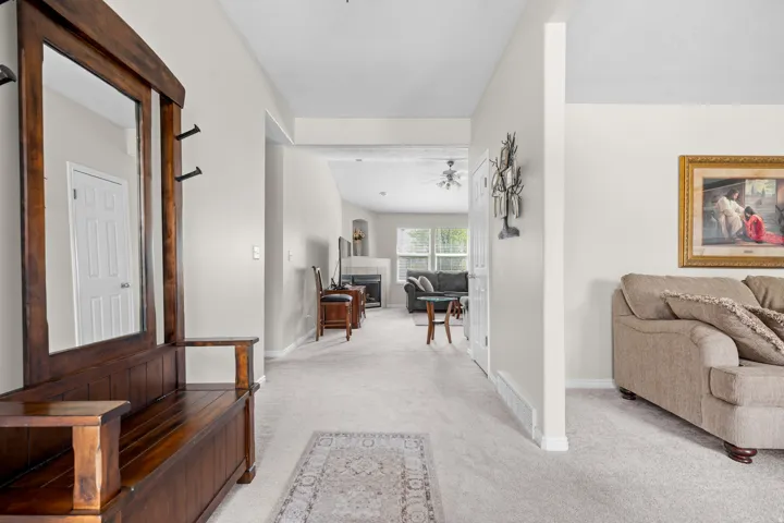 Carpeted Entry, Light-colored walls, and a fireplace with a stone surround
