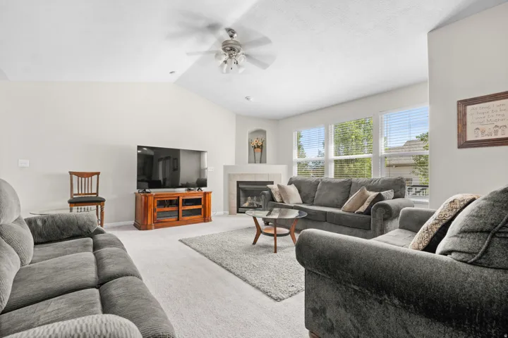 Vaulted ceiling with a ceiling fan, recessed lighting, fireplace with a mantel, and multiple windows with blinds