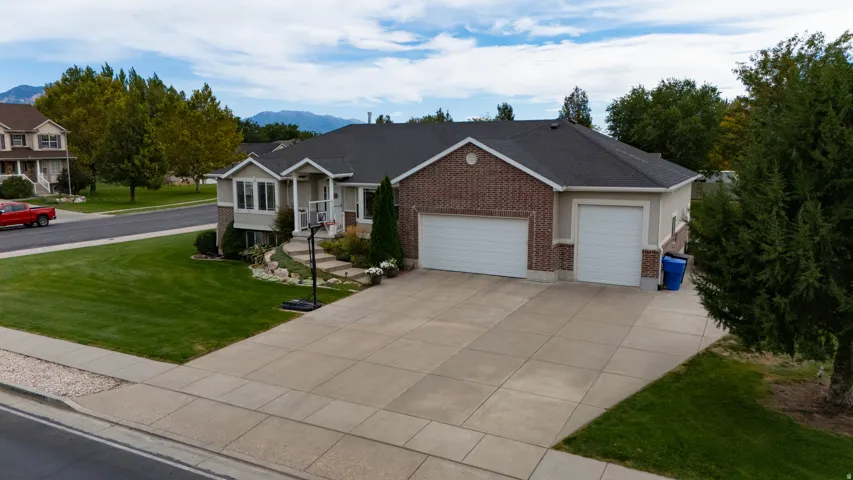 Two-car garage with white doors, brick and stucco exterior, dark asphalt shingle roof, concrete driveway, and a front lawn