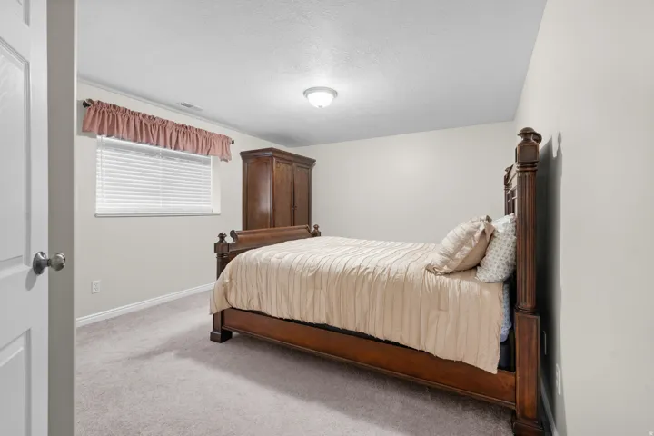 Basement bedroom, carpeted flooring, white walls, and a ceiling-mounted light fixture
