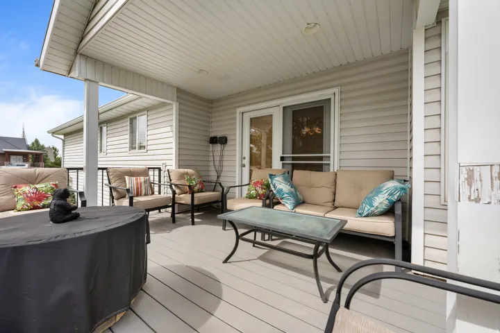 Covered oversized custom trex deck with composite decking, white vinyl siding, white ceiling panels, and black metal railings
