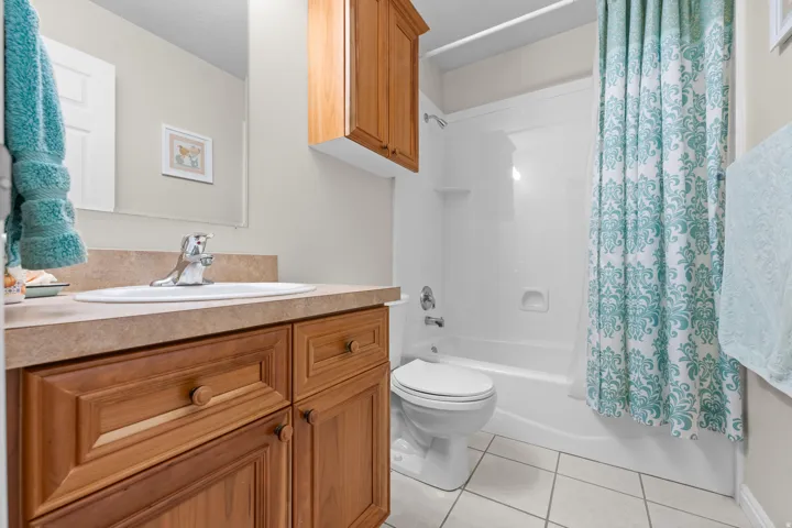 Bathroom featuring a vanity with a drop-in sink, a built-in wood-finish cabinet, and a shower-tub combination