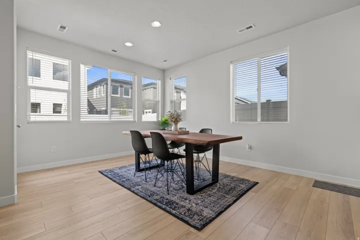 Recessed lighting, wood-finish flooring, multiple windows with blinds, and white wall finishes