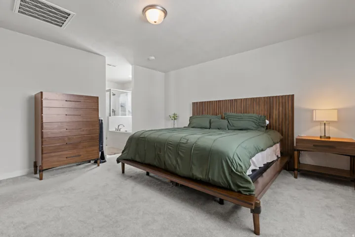 Spacious primary bedroom with a ceiling-mounted light fixture and a window with blinds