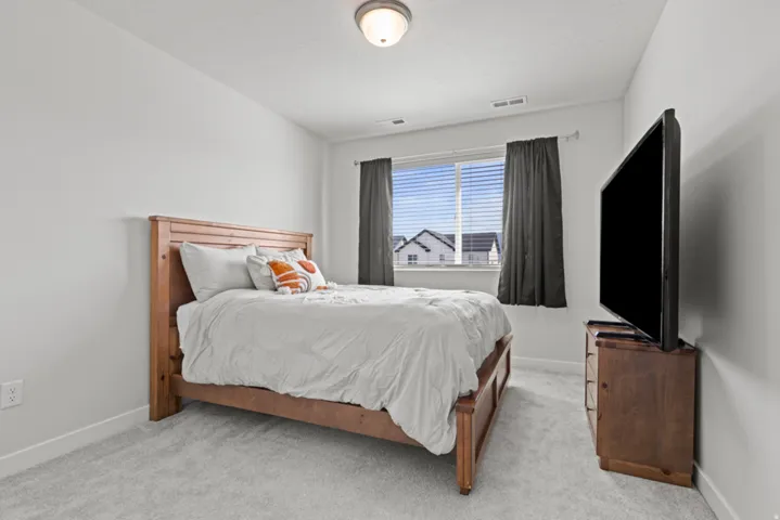2nd bedroom with white painted walls, light carpet, and a single window featuring blinds and dark curtains