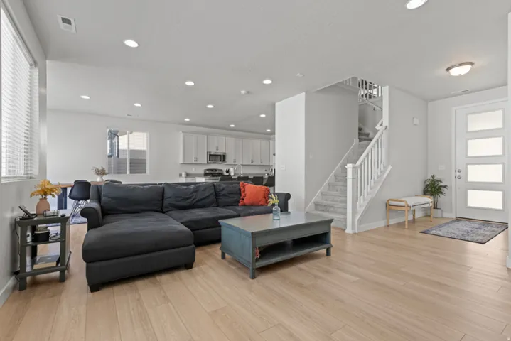 Open concept living space featuring wood-finish flooring, recessed lighting, and a contemporary front entry door with frosted panels