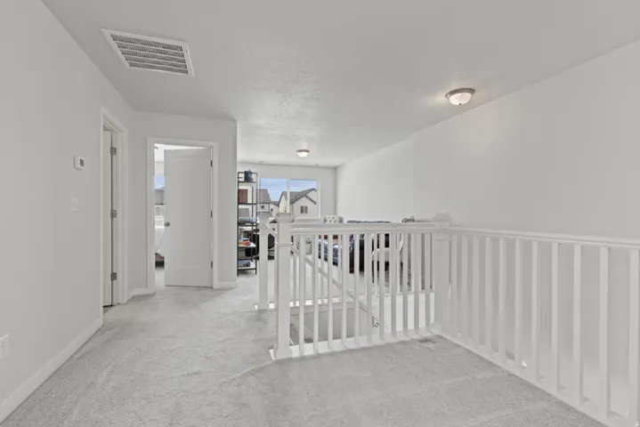 White painted balustrade, light carpet flooring, white painted walls, and recessed lighting