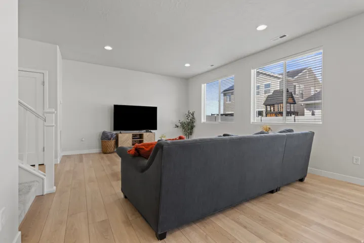Recessed lighting, light wood-finish flooring, white walls, and a staircase with white balusters