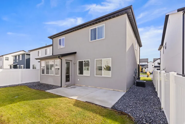 Private backyard featuring a concrete patio, grassy area, and white vinyl fencing