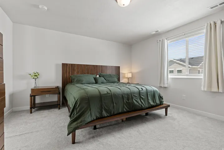 Spacious primary bedroom with a ceiling-mounted light fixture and a window with blinds