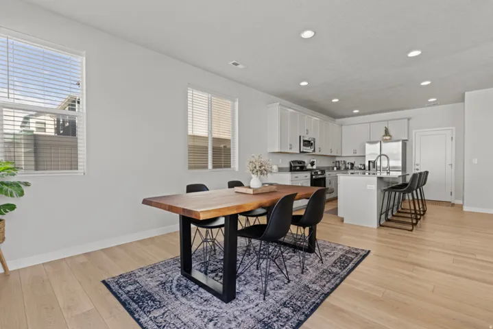 Open-concept living area with light wood-finish flooring, white walls, and recessed lighting
