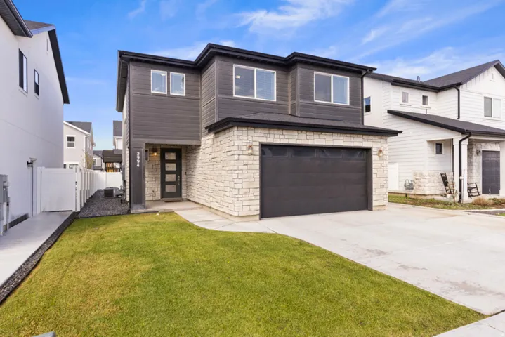 Contemporary two-story exterior with stone veneer and dark siding, featuring a two-car garage, and a concrete driveway -
